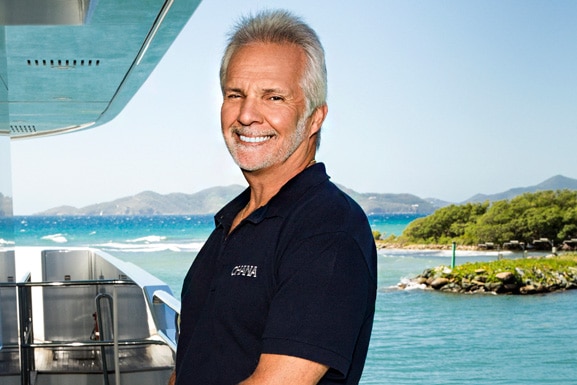 Captain Lee smiles and wears a blue polo while on yacht