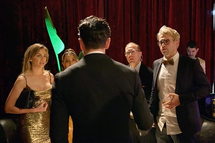 Tom Sandoval talking to his castmates and a producer in front of a red curtain.