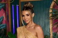 Scheana Shay wearing an off the shoulder gold dress in front of a palm.