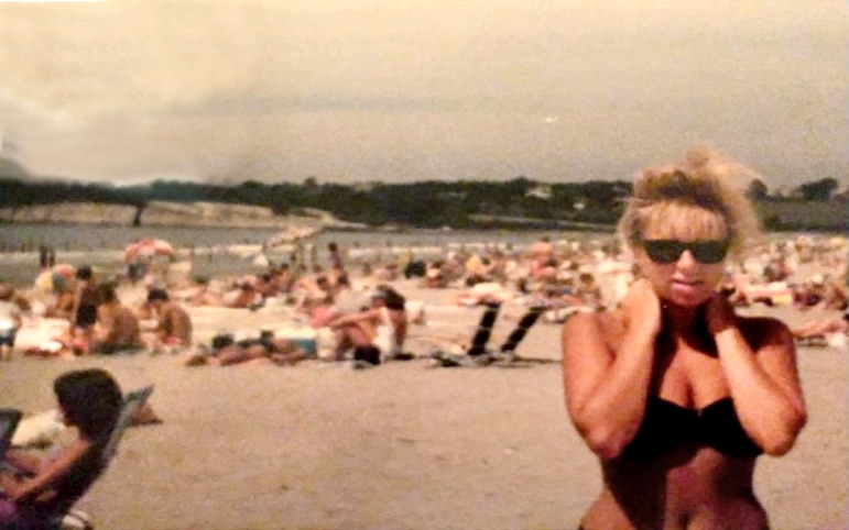 Margaret Josephs on the beach wearing a black bikini.