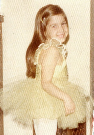 Young Jacqueline Laurita posing in a yellow ballet dress.