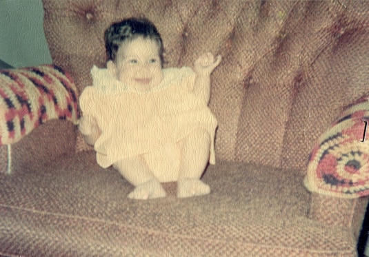 Baby Jacqueline Laurita laughing on the couch.