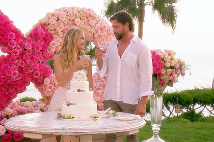 Denise Richards and Aaron Phypers standing together by their wedding cake.