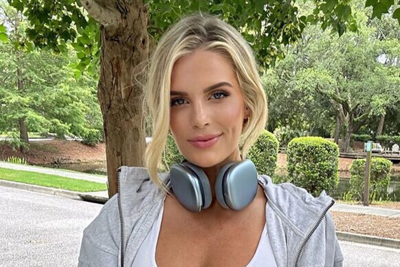 Madison wearing headphones, a gray hoodie, and a white bra top outdoors.