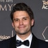 Tom Schwartz standing in front of a step and repeat.