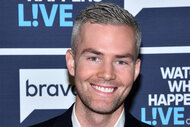 Ryan Serhant smiling in front of a step and repeat at WWHL.