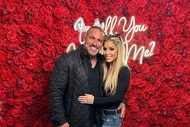 Frank Catania and Brittany Mattessich posing and smiling in front of a wall of roses.