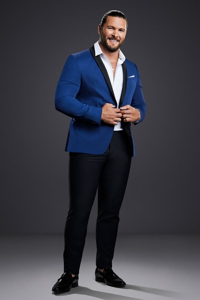 Brock Davies posing in a blue blazer in front of a grey backdrop.