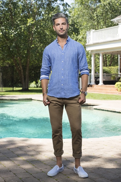 Amit Neuman wearing a blue shirt and brown pants in front of a pool.