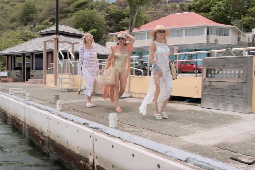 Kristen Taekman, Sonja Morgan, and Ramona singer walk down a boardwalk wearing beachwear on The Real Housewives Ultimate Girls Trip Season 4 Episode 4.