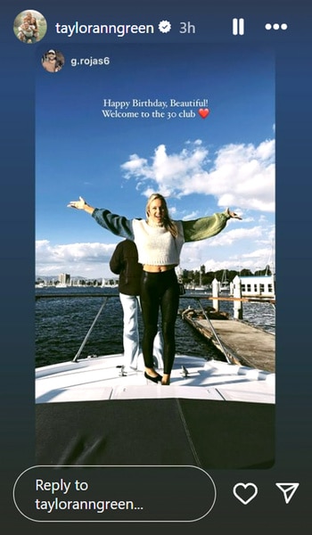 Taylor Ann Green on a boat with her hands up in celebration for her birthday.
