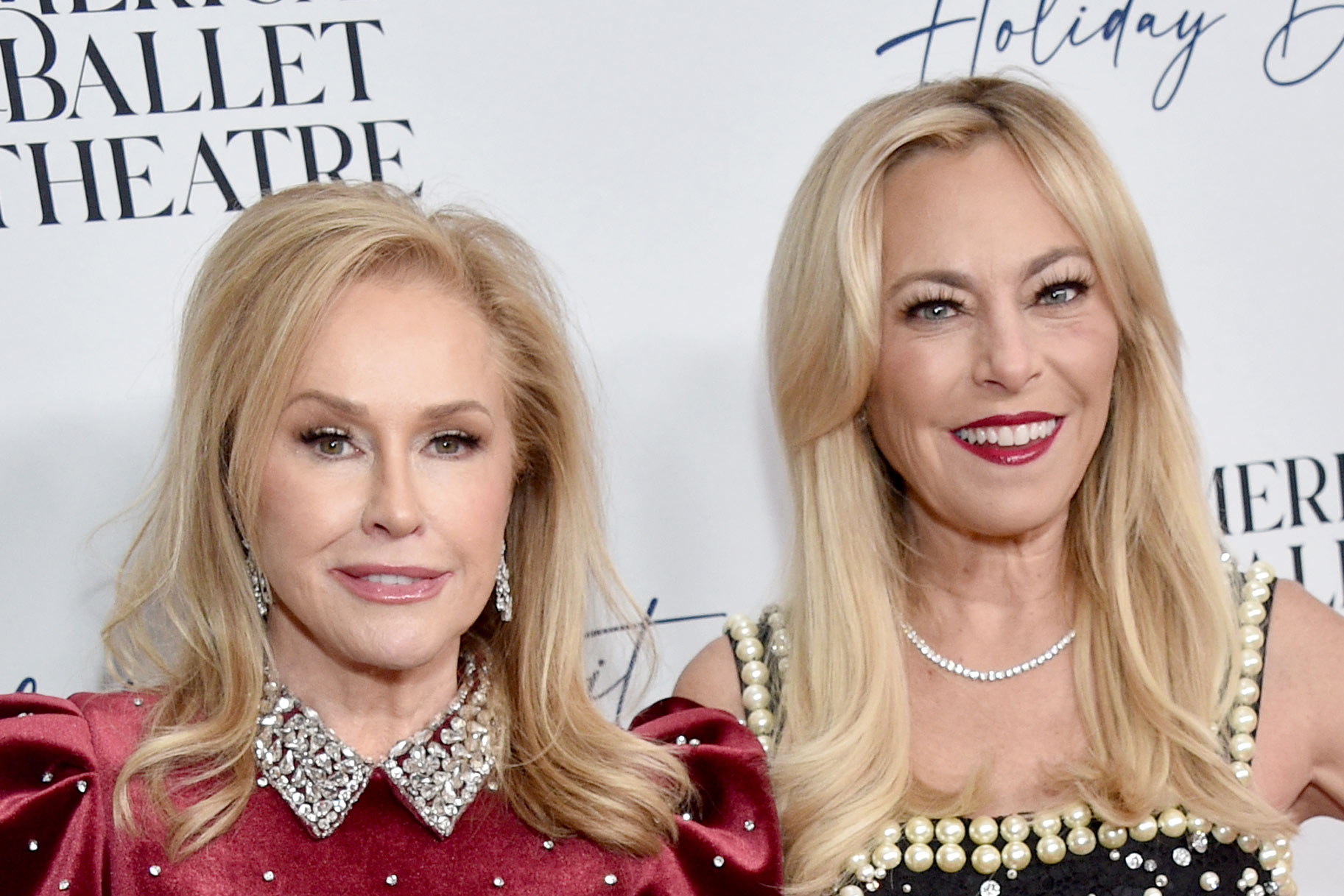 Sutton Stracke and Kathy Hilton posing in front of a step and repeat.