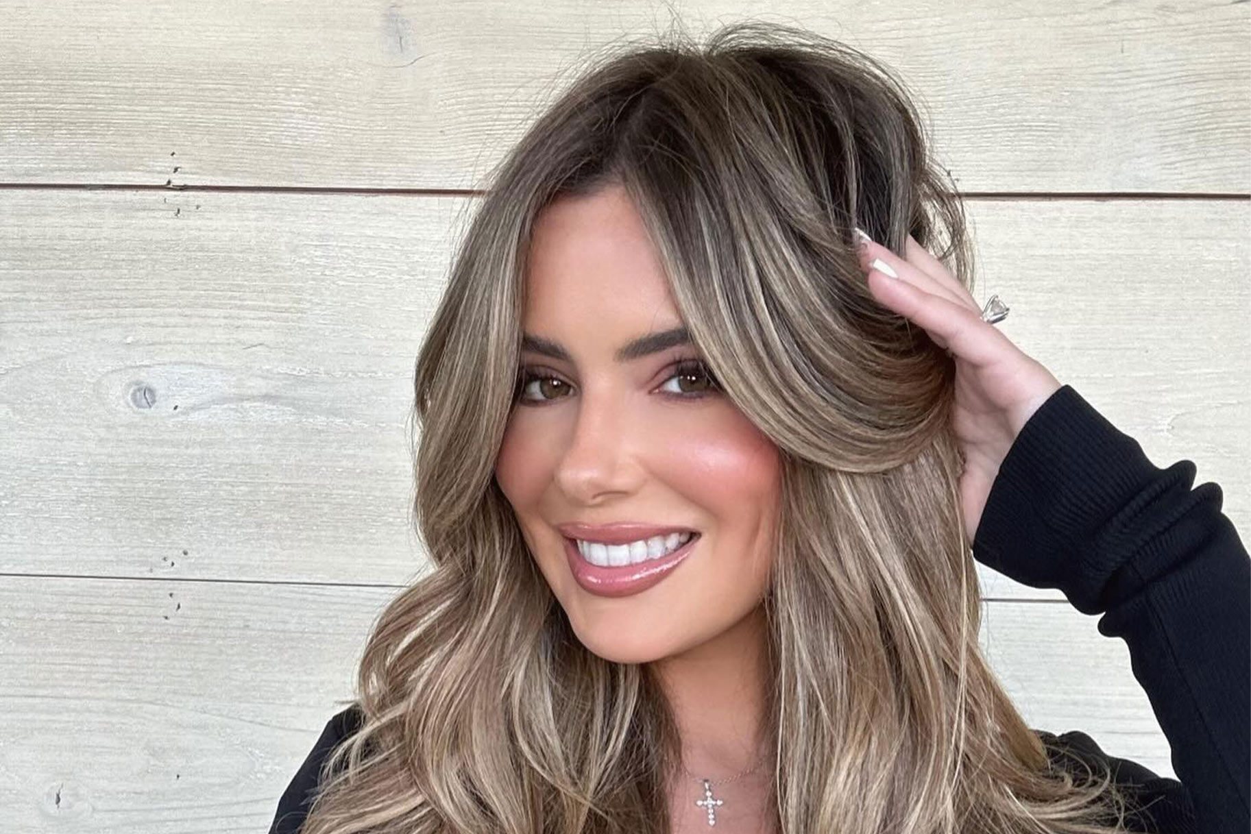 Brielle Biermann smiling in front of a wooden wall.