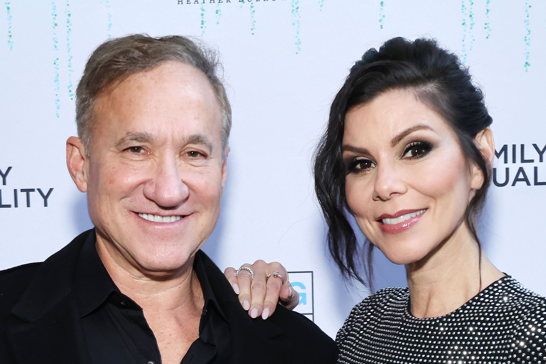 Heather Dubrow and Terry Dubrow smiling in front of a step and repeat.