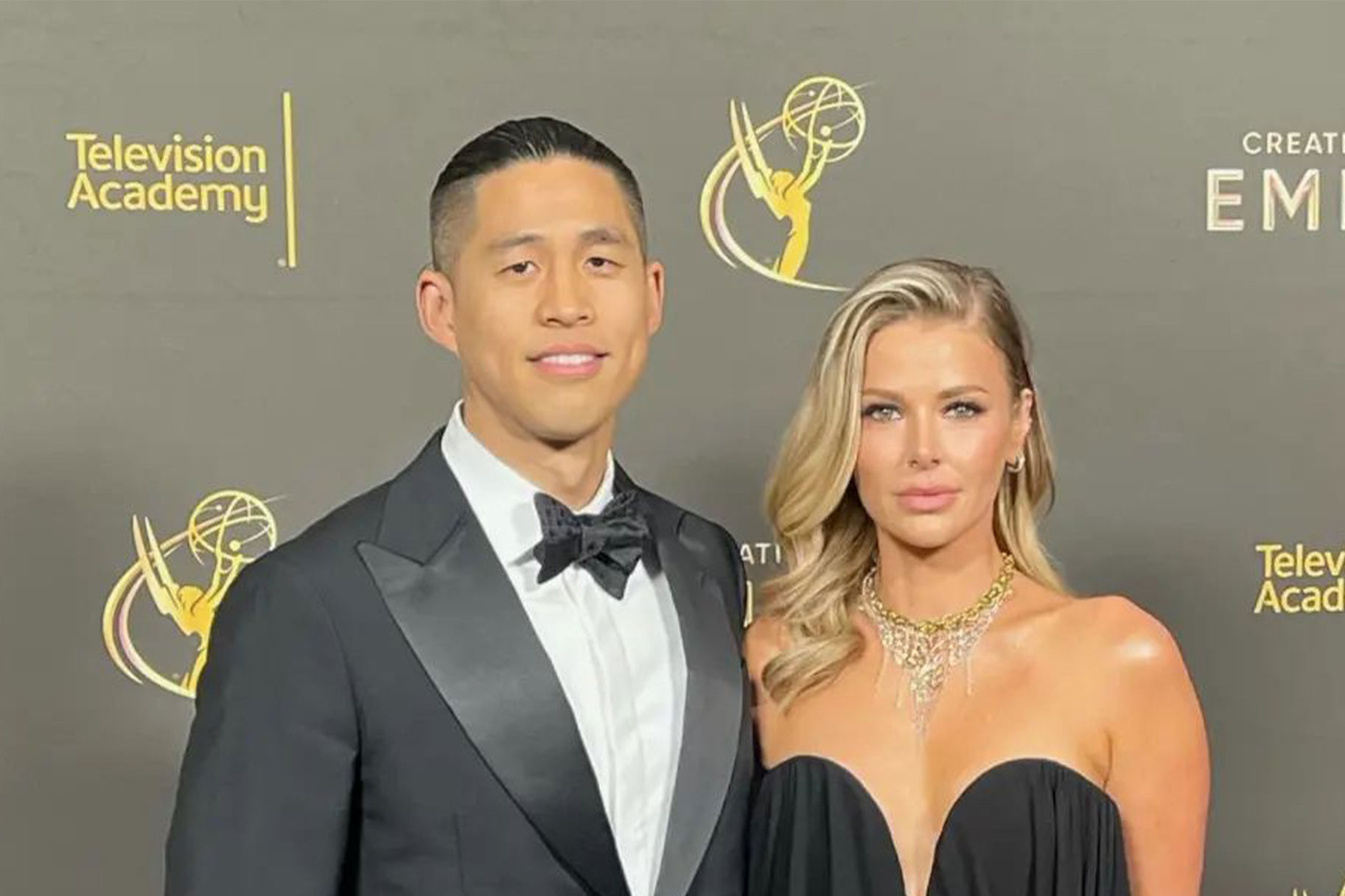 Ariana Madix and Daniel Wai posing together in front of a step and repeat.