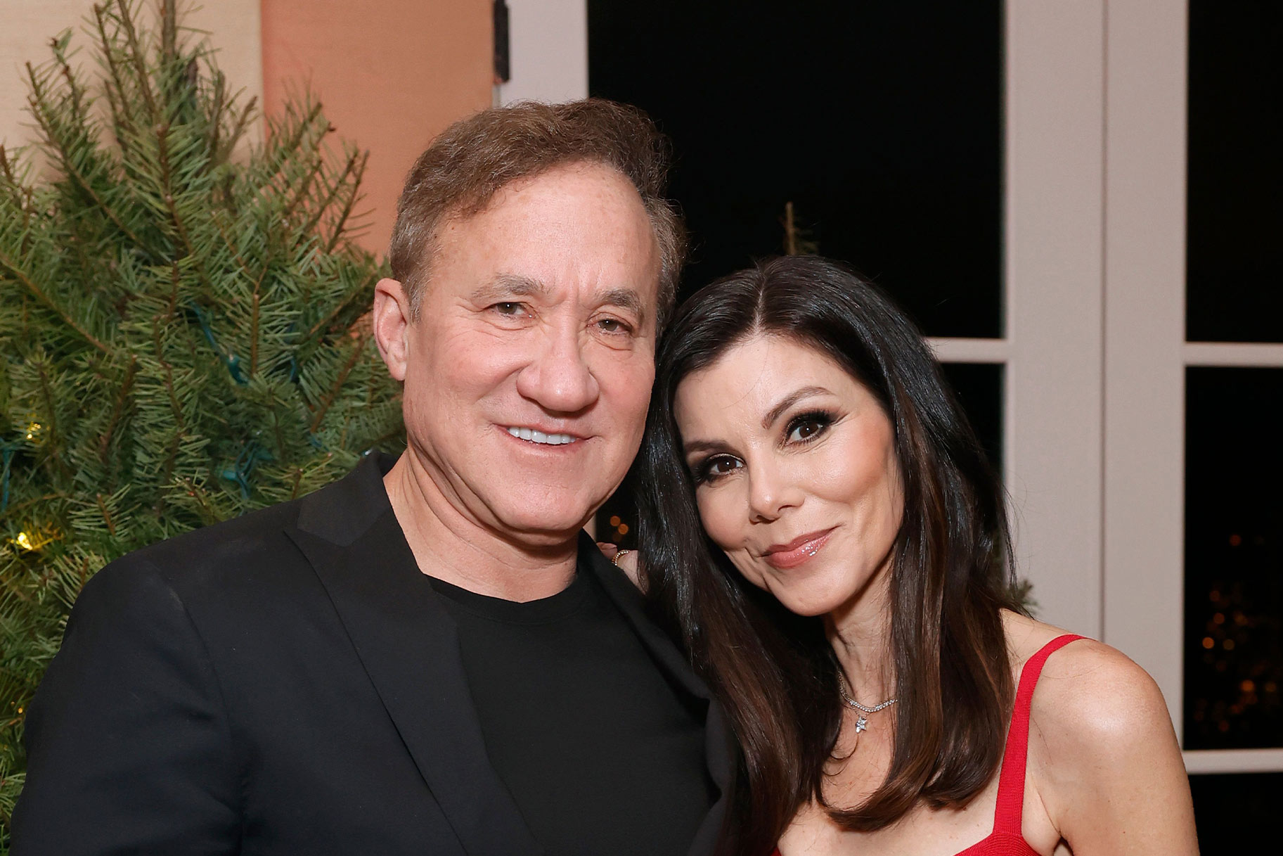 Heather Dubrow and Terry Dubrow smiling next to each other in front of a Christmas tree.