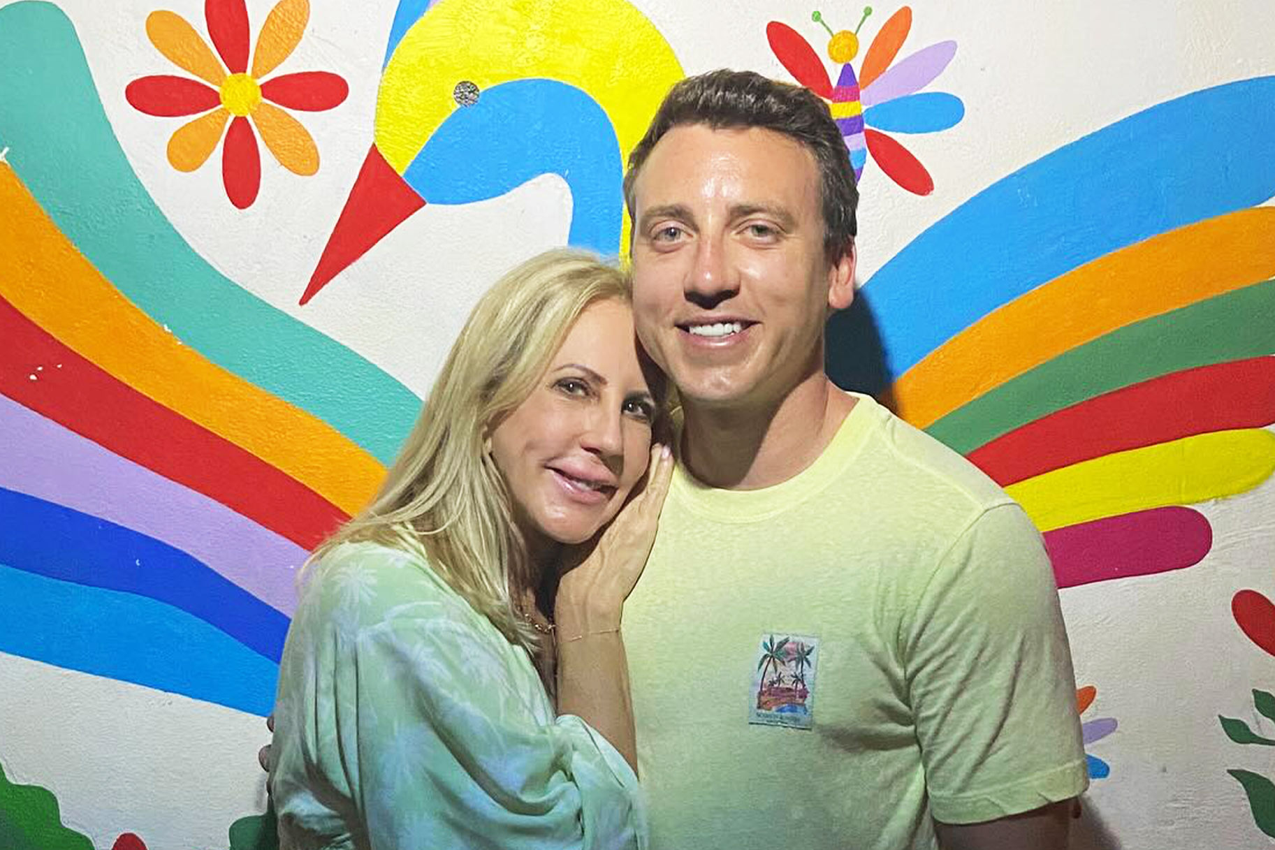 Vicki Gunvalson and son, Michael Wolfsmith, posing together in front of a wall mural.