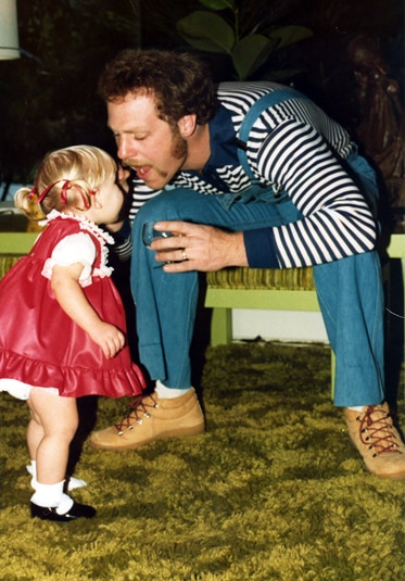 Gretchen Rossi as a baby standing next to her father.