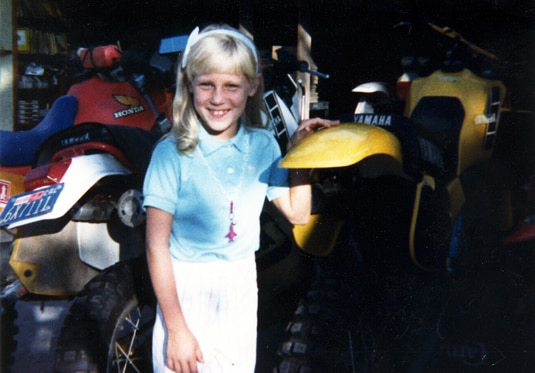 Gretchen Rossi standing next to an off road vehicle as a child.