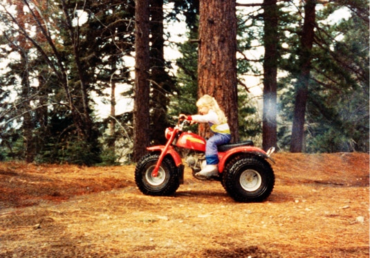 Gretchen Rossi riding a four wheeler as a child through the woods.