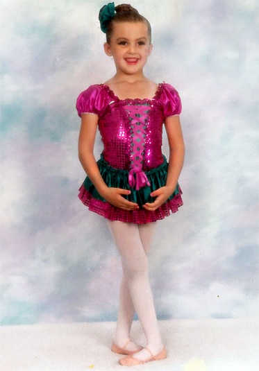 A young Ashlee Holmes wearing a magenta sequin ballet dress and slippers