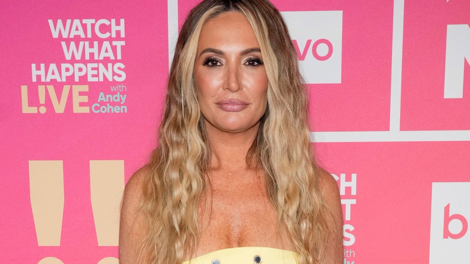 Kate Chastain wearing a yellow strapless dress in front of a WWHL step and repeat.