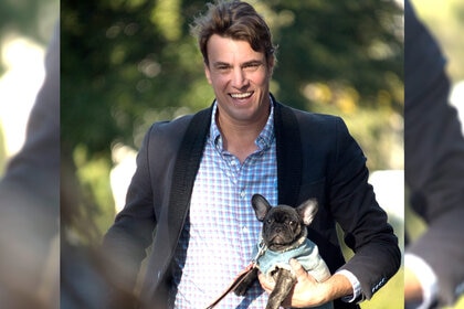 Shep Rose carrying his dog Lil Craig while at a party in Charleston, South Carolina.