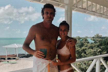 Shep Rose and Taylor Green wearing bathing suits, posing while at the beach.