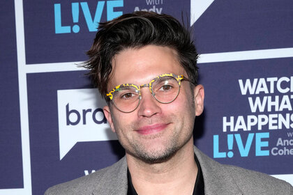 Tom Schwartz stands in front of the Watch What Happens Live step and repeat