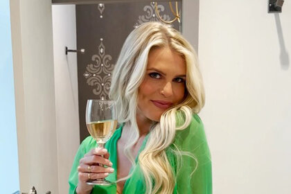 Madison in a green outfit holding a glass of white wine.