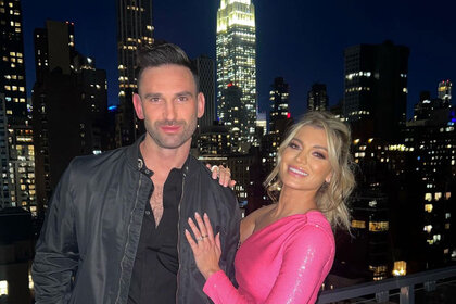 Lindsay Hubbard and Carl Radke pose on a balcony in New York City at night.