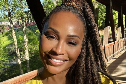 Cynthia smiling outdoors with an updo.