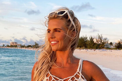 Madison in a white beaded bikini and sunglasses on a beach.