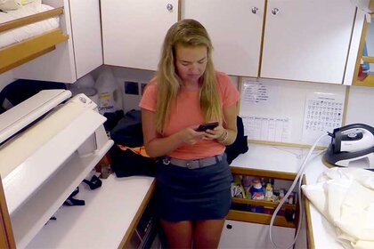 Daisy Kelliher texts on her phone in the laundry room of the boat on Below Deck Sailing Yacht