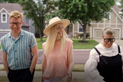 Johan, Katarina, and Ella stand together smiling and laughing outdoors.