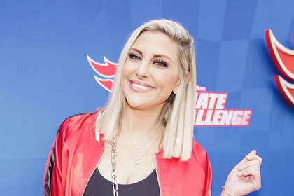 Gina Kirschenheiter poses in front of a step and repeat at an event.