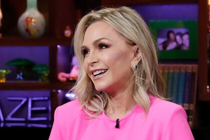 Tamra Judge laughing at Watch What Happens Live in a bright pink look.