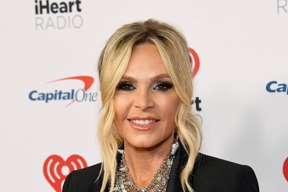 Tamra Judge smiling in front of a step and repeat at an event.