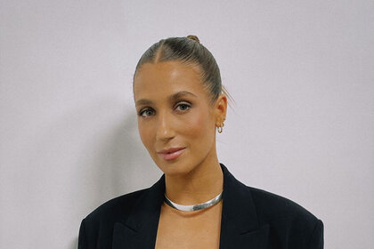 Amanda with a slicked back bun wearing a black blazer and silver choker necklace.