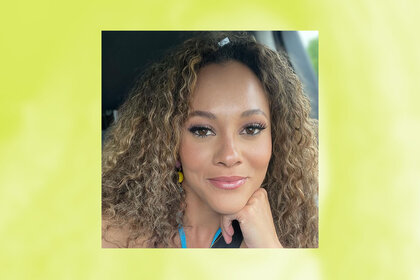 Ashley Darby takes a selfie in a car wearing a bright blue halter top and dangling earrings.