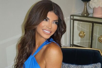 Teresa seated and smiling wearing a blue halter top.