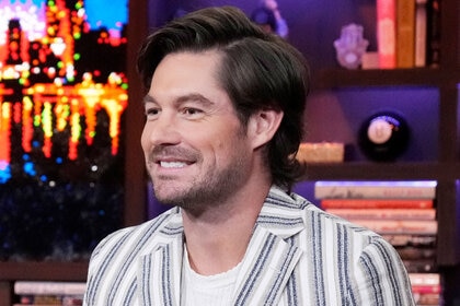 Craig Conover smiling in a striped suit and white, knitted, shirt at WWHL in New York City.