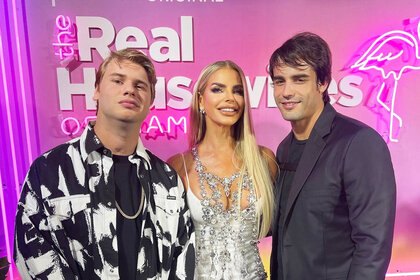 Alexia Nepola, Peter Rosello, and Frankie Rosello pose together in front of a pink sign.