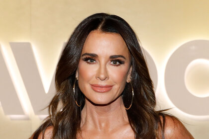 Kyle Richards posing in front of a sign at BravoCon 2023.