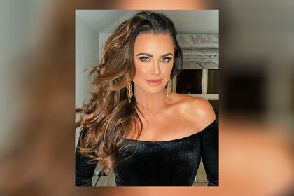 Kyle Richards wearing a boat neck black top wearing full glam.