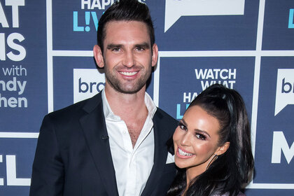 Scheana Shay and Carl Radke pose together in front of the Watch What Happens Live step and repeat in New York City.