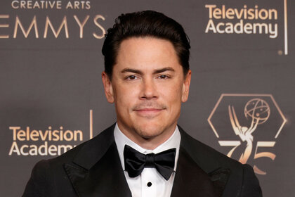 Tom Sandoval smiling in front of a step and repeat.