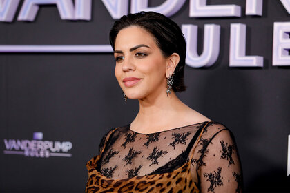 Katie Maloney wearing a leopard print dress in front of a step and repeat.