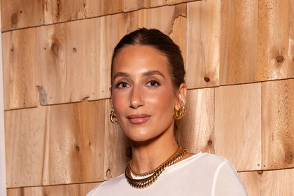 Amanda Batula posing in a white dress in front of a themed set.