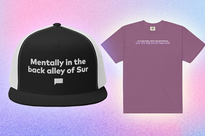 A mesh baseball cap and a purple tee on a pastel blue and pink background.